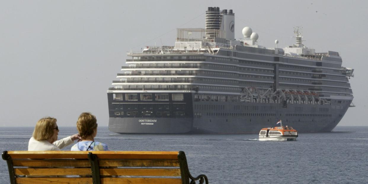 Two women sit on a bench at a promenade of the western seaside town of Loutraki as the 954 cabin, ten deck Oosterdam line cruise ship is seen at the background in 2003 (file photo)..JPG