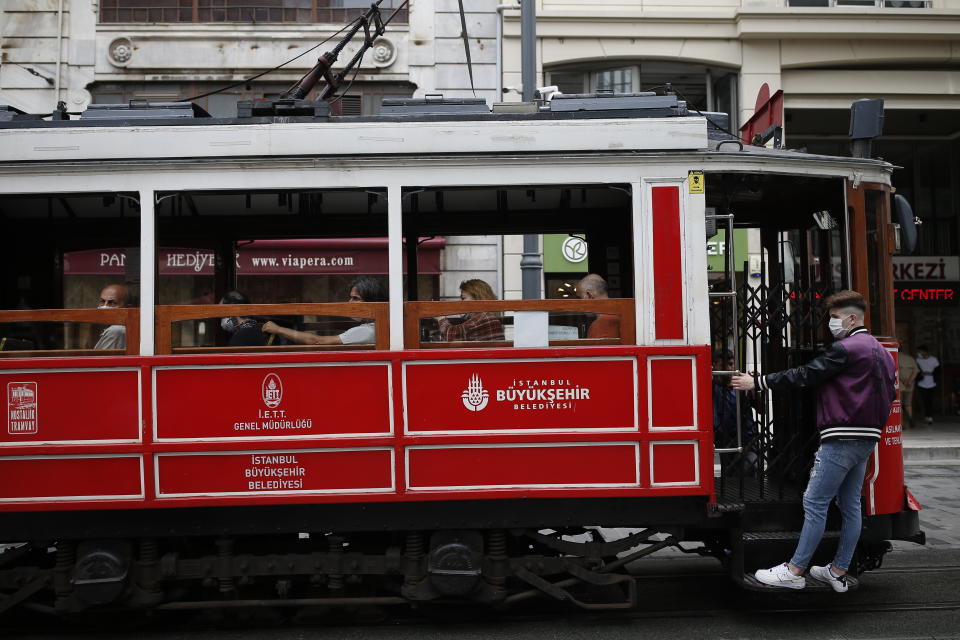 People, wearing protective masks against the spread of coronavirus, use the tram on Istiklal street, the main shopping street in Istanbul, Thursday, June 18, 2020. Turkish authorities have made the wearing of masks mandatory in Istanbul, Ankara and Bursa to curb the spread of COVID-19 following an uptick in confirmed cases since the reopening of many businesses. (AP Photo/Emrah Gurel)