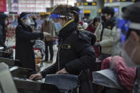 A woman wearing a face mask and face shield to help curb the spread of the coronavirus prepares to board her train at the South Train Station in Beijing, Thursday, Jan. 28, 2021. Efforts to dissuade Chinese from traveling for Lunar New Year appeared to be working. Beijing's main train station was largely quiet on the first day of the travel rush and estimates of passenger totals were smaller than in past years. (AP Photo/Andy Wong)