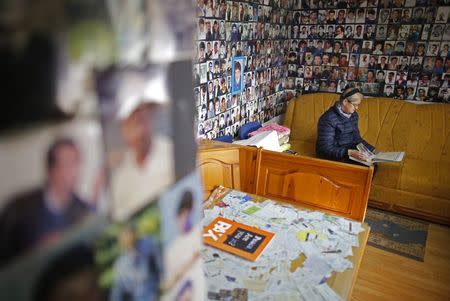 Hajra Catic looks at pictures in a book as she sits under pictures of victims of the genocide in Tuzla, December 23, 2014. REUTERS/Dado Ruvic