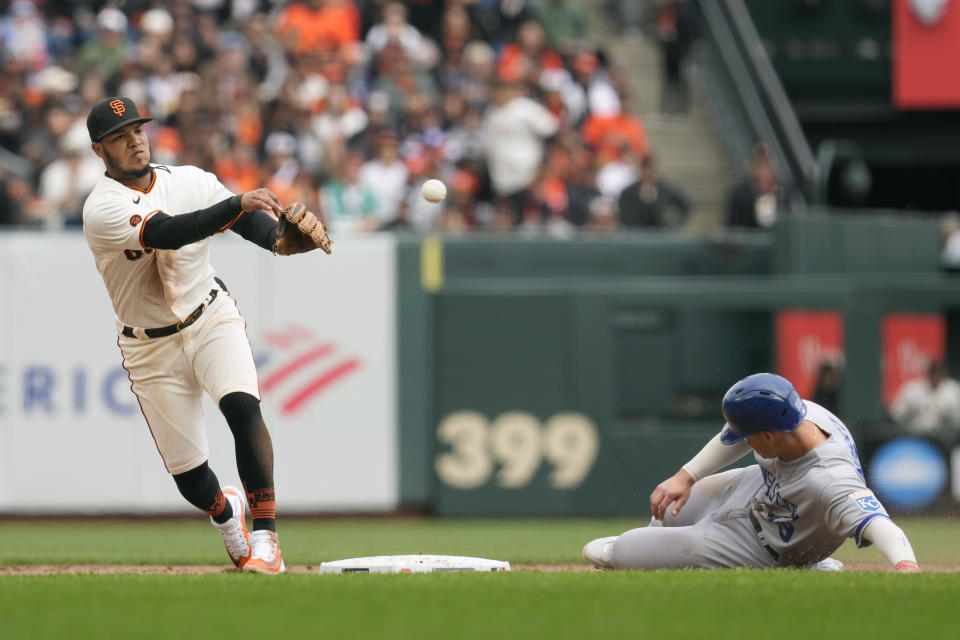 San Francisco Giants second baseman Thairo Estrada, left, throws to first base after forcing Kansas City Royals' Michael Massey, right, out at second base on a double play hit into by Salvador Perez during the third inning of a baseball game in San Francisco, Friday, April 7, 2023. (AP Photo/Eric Risberg)