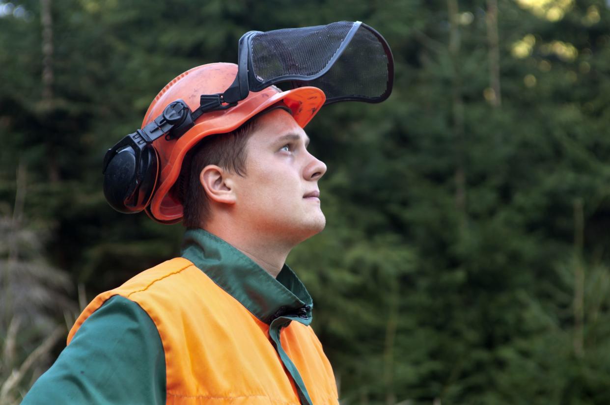 Portrait of young lumberjack looking up. Side view on blur background.