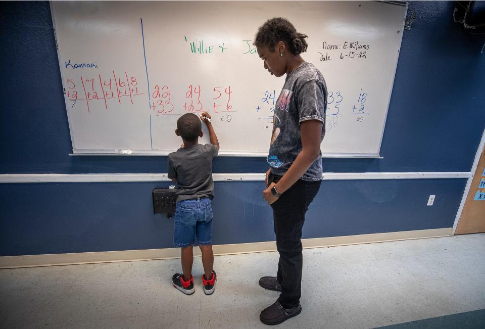 Shelby Reeves helps Willie Evans, 7, with some math problems at the B Street Community Service Center in Lake Wales Fl. Wednesday June 15,  2022. The Green & Gold Foundation hosts summer interns from Polk high schools and out of school ages 16-24 to teach kids in Lake Wales who are behind in school.ERNST PETERS/ THE LEDGER