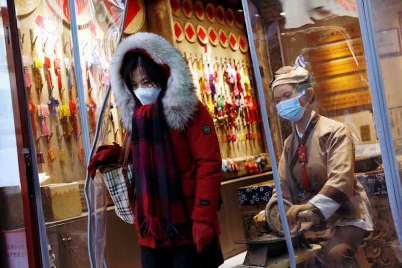 A woman wearing a protective mask leaves a shop along Yandaixiejie alley following the coronavirus disease (COVID-19) outbreak in Beijing