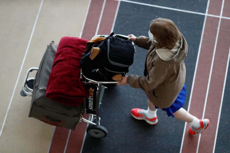 A woman wearing a face mask walks along the main terminal of Ronald Reagan Washington National Airport as the World Health Organization said for the first time on Wednesday that it now sees the coronavirus outbreak as a pandemic, in Washington, U.S.