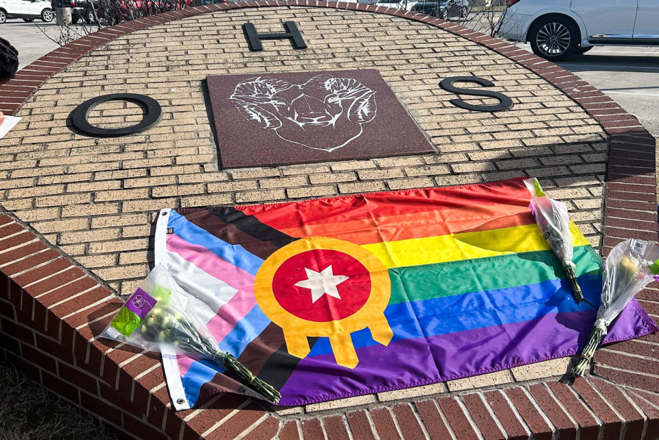 A pride flag and flower bouquets are laid atop the school entry plaque for Owasso High School (Jo Yurcaba / NBC News)