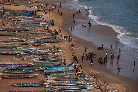 People are pictured on a beach next to fishing canoes in Dakar, Senegal, June 21, 2013. REUTERS/Joe Penney