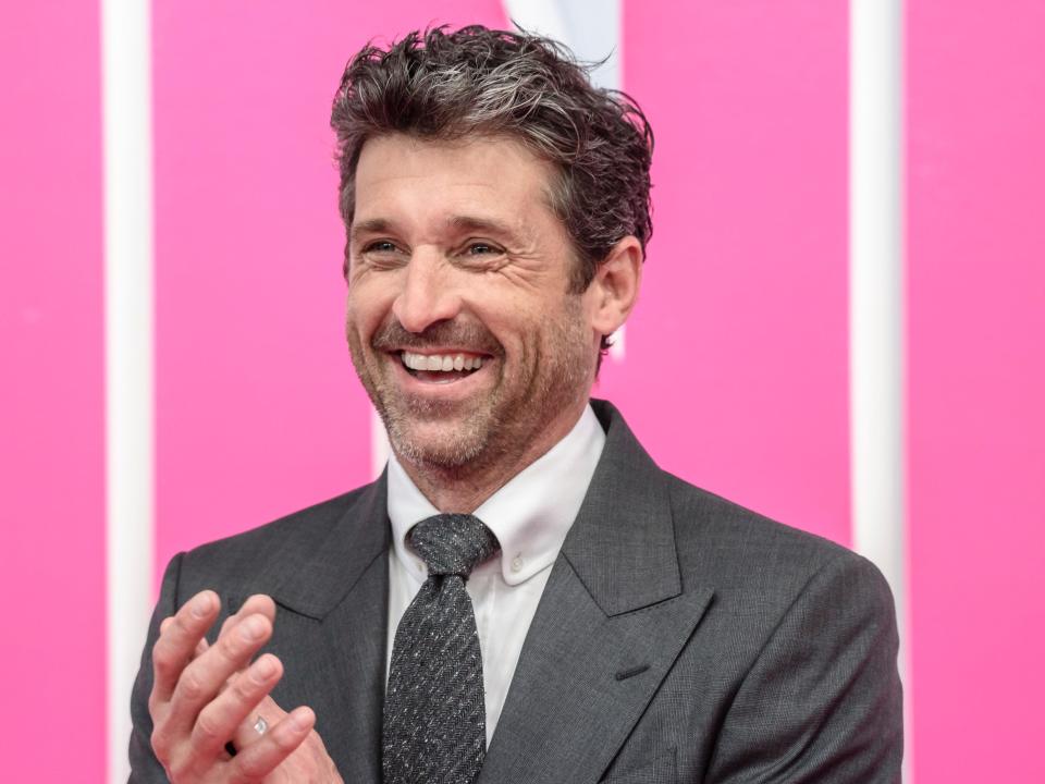 Patrick Dempsey smiles against a pink background