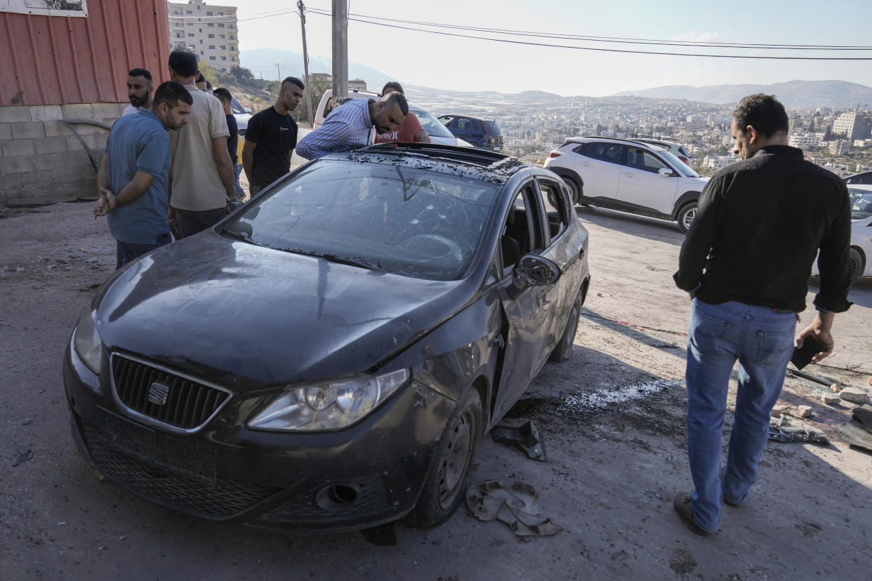 Palestinians look at a damaged car following an Israeli airstrike in Tubas, West Bank, Thursday, Sept. 5, 2024. Palestinian health officials say Israeli strikes in the occupied West Bank killed five people. Israel has been carrying out large-scale raids in the territory over the past week that it says are aimed at dismantling militant groups and preventing attacks. (AP Photo/Majdi Mohammed)