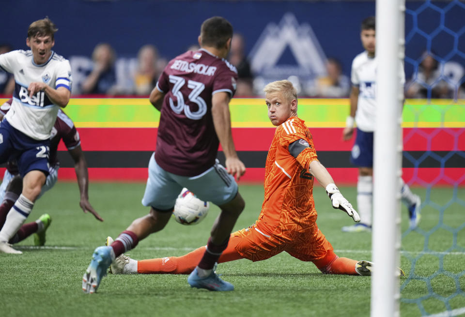 Colorado Rapids goalkeeper William Yarbrough, right, watches as Steven Beitashour (33) prevents a shot by Vancouver Whitecaps' Ryan Gauld, left, from entering the goal during the second half of an MLS soccer match Wednesday, Aug. 17, 2022, in Vancouver, British Columbia. (Darryl Dyck/The Canadian Press via AP)