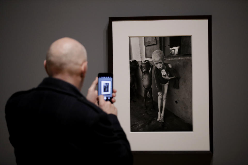 A visitor takes a photo of a 1968 photograph of a starving albino boy in Biafra by veteran British conflict photographer Don McCullin at the launch of his retrospective exhibition at the Tate Britain gallery in London, Monday, Feb. 4, 2019. The exhibition includes over 250 of his black and white photographs, including conflict images from the Vietnam war, Northern Ireland, Cyprus, Lebanon and Biafra, alongside landscape and still life images. (AP Photo/Matt Dunham)