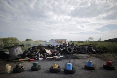 French labour union employees stand near a smoking barricade to block the entrance of the fuel depot of the SFDM company near the oil refinery of Donges, France, May 25, 2016 in protest over proposed new labour laws. REUTERS/Stephane Mahe