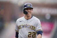 Milwaukee Brewers' Christian Yelich jokes with first base coach Quintin Berry after Yelich drew a walk from Colorado Rockies starting pitcher German Marquez during the first inning of a baseball game Thursday, June 17, 2021, in Denver. (AP Photo/David Zalubowski)