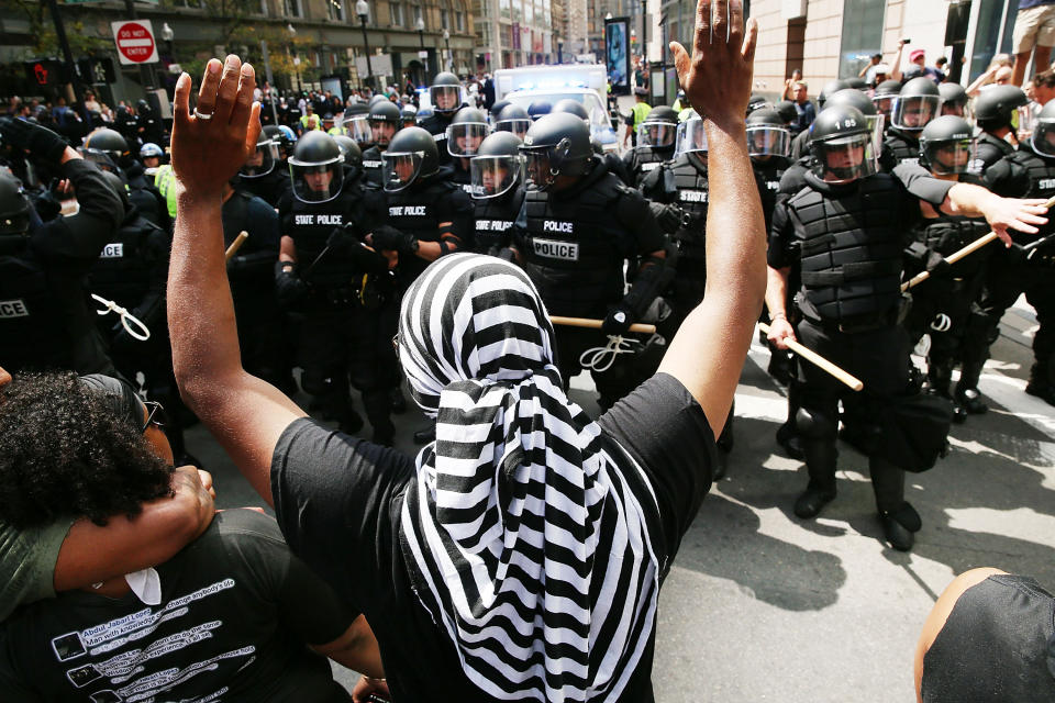 <p>A counter-protester throws his hands up while facing off against police.</p>