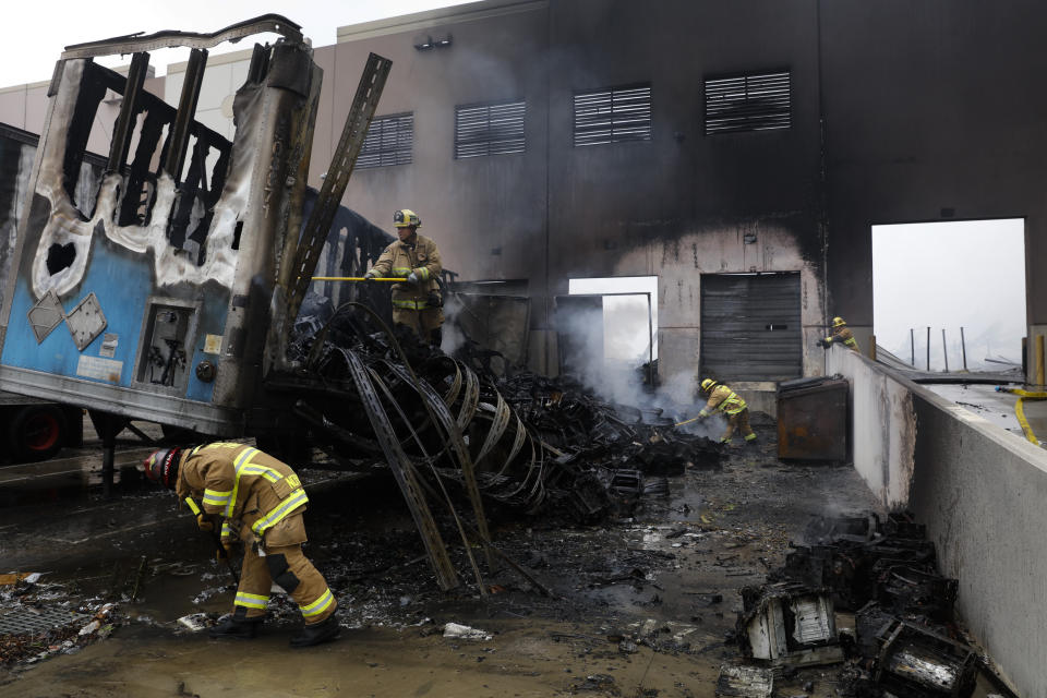 Firefighters put out hot spots at a warehouse destroyed in a fire, Friday, June 5, 2020, in Redlands, Calif. The fire destroyed the Southern California distribution facility that was used to ship items to Amazon customers but authorities said employees got out and there were no reports of injuries. (AP Photo/Jae C. Hong)