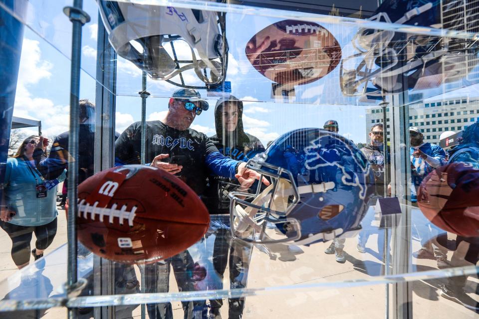 Detroit Lions fans look at memorabilia to bid on for the auction during the NFL experience at Hart Plaza in Detroit on Thursday, April 25, 2024.