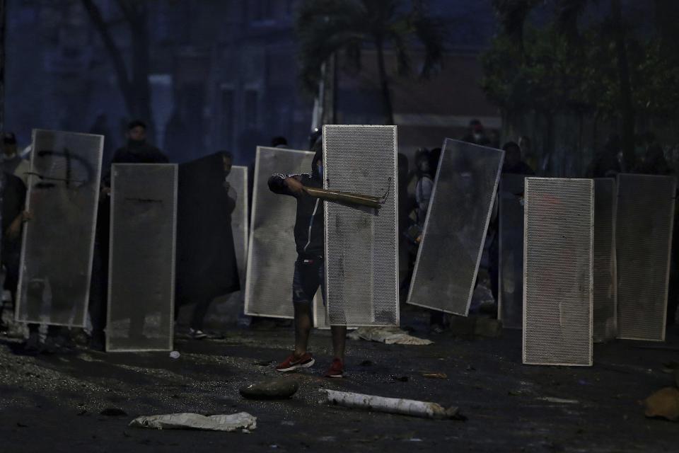 Los manifestantes se protegen con escudos improvisados en enfrentamientos con la policía durante un paro nacional para protestar por la reforma tributaria propuesta por el gobierno del presidente Iván Duque, en Cali, Colombia, el viernes 30 de abril de 2021. (AP Foto/Andrés González)