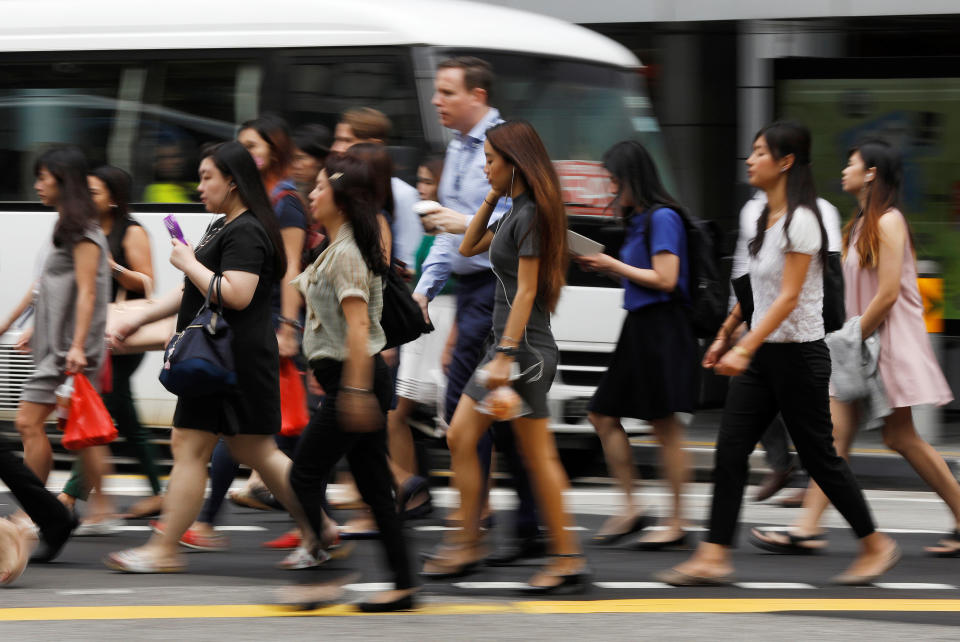 Office workers cross a street in Singapore's central business district April 27, 2017.  REUTERS/Edgar Su