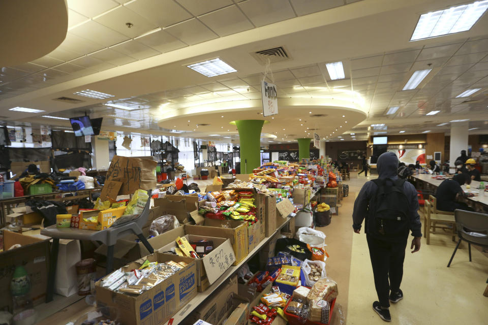 A protester walks through a room with food and other supplies at the Hong Kong Polytechnic University in Hong Kong, Saturday, Nov. 16, 2019. Rebellious students and anti-government protesters abandoned their occupation of at least one major Hong Kong university after a near weeklong siege by police, but some other schools remained under control of demonstrators on Saturday. (AP Photo/Achmad Ibrahim)