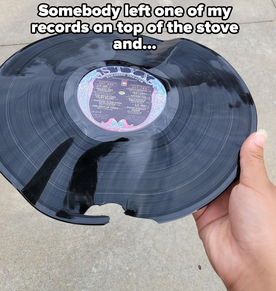 A hand holding a damaged vinyl record with a visible label