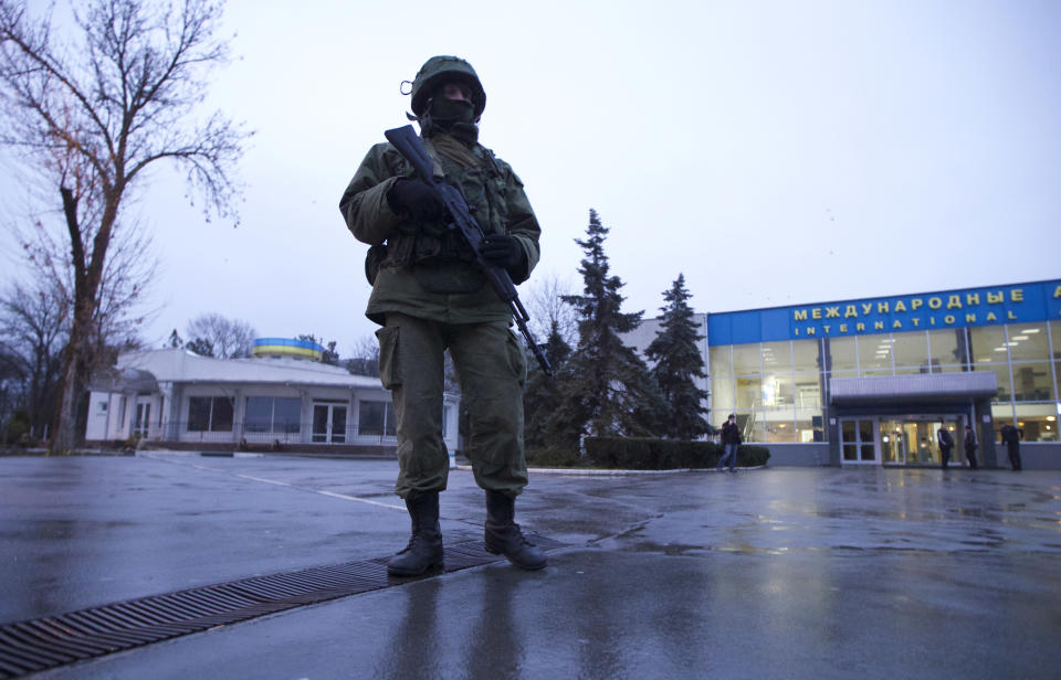 An unidentified armed man patrols a square in front of the airport in Simferopol, Ukraine, on Friday, Feb. 28, 2014. Dozens of armed men in military uniforms without markings occupied the airport in the capital of Ukraine's strategic Crimea region early Friday. (AP Photo/Ivan Sekretarev)