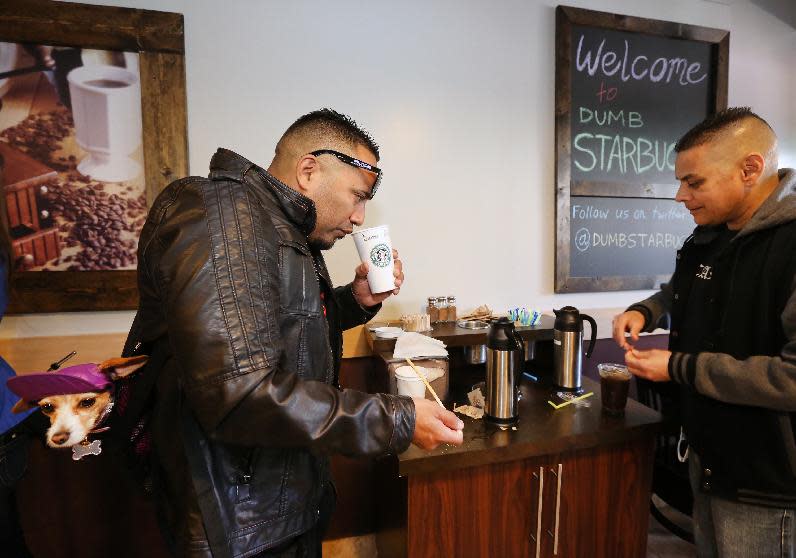 Anthony Solis, left, and Tony Gonzalez prepare their coffee at the Dumb Starbucks coffee shop in Los Angeles Monday, Feb. 10, 2014. The store resembles a Starbucks with a green awning and mermaid logo, but with the word "Dumb" attached above the Starbucks sign. Spokeswoman Laurel Harper says the store is not affiliated with Starbucks and, despite the humor, the store cannot use the Starbucks name. (AP Photo/Damian Dovarganes)