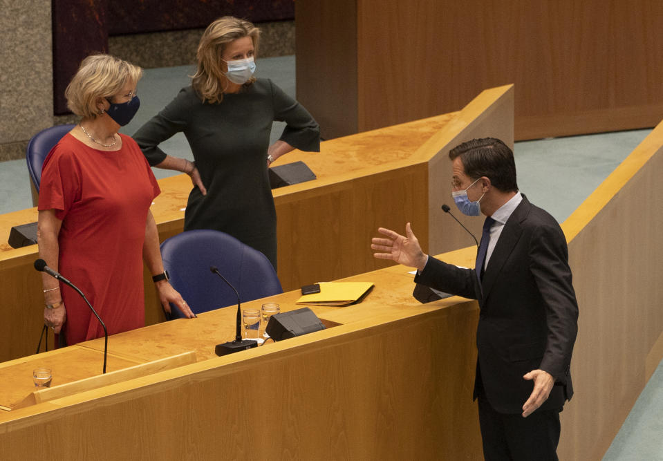 Caretaker Dutch Prime Minister Mark Rutte, right, talks to the two officials who led the coalition talks, caretaker interior minister Kajsa Ollongren, right, and Senator Annemarie Jorritsma, left, during a debate on Rutte's role in the talks in The Hague, Netherlands, early Friday, April 2, 2021. Rutte was fighting for his political life in a bitter parliamentary debate about the country's derailed process of forming a new ruling coalition following elections last month. (AP Photo/Peter Dejong)