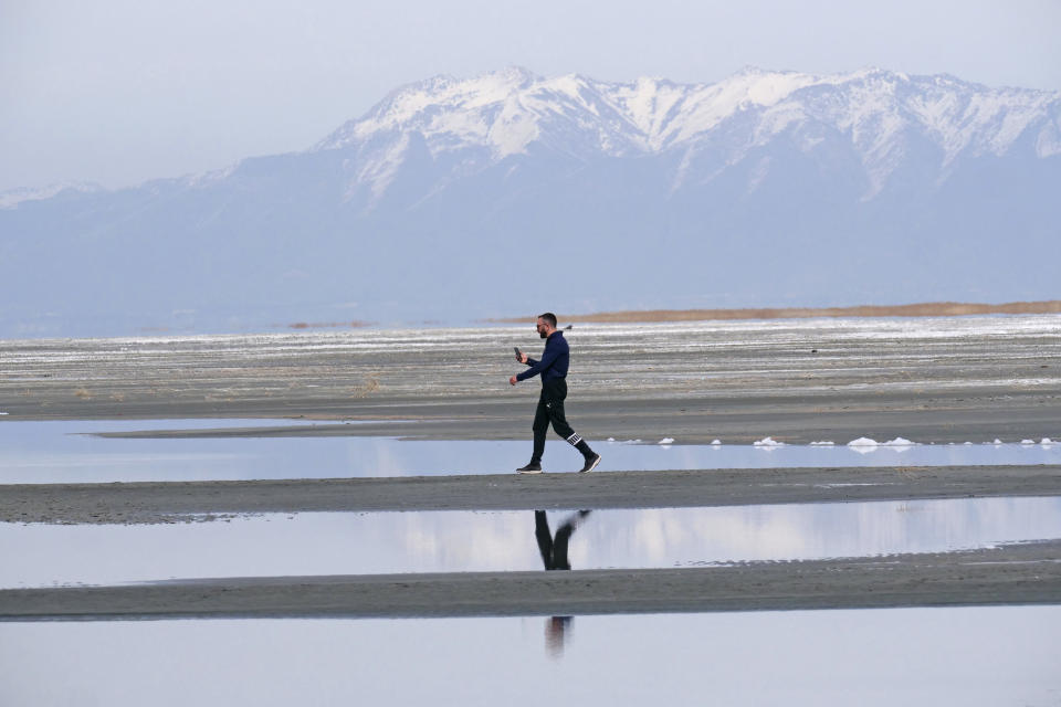 Ruben Gyoeltsyan walks across a sand bar at the receding edge of the Great Salt Lake Thursday, March 3, 2022, near Salt Lake City. Utah lawmakers passed a $40 million proposal through the state Senate that would pay water rights holders to conserve and fund habitat restoration to prevent the lake from shrinking further. (AP Photo/Rick Bowmer)