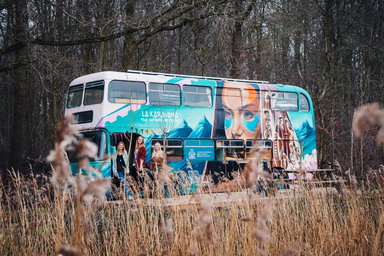 a double-decker bus with three women standing outside of it