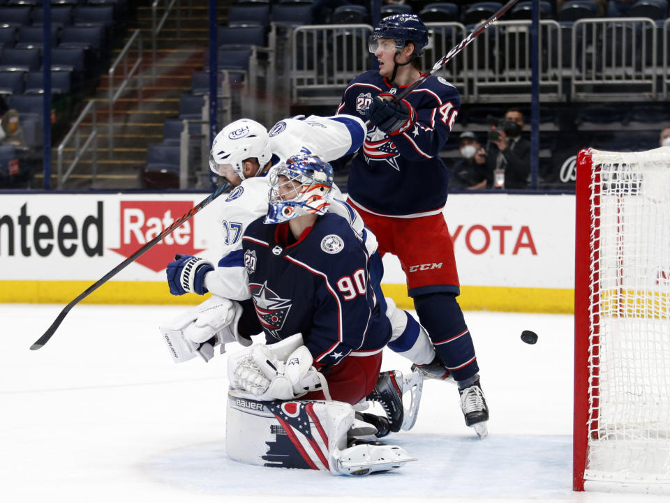 Tampa Bay Lightning forward Alex Killorn, left, collides with Columbus Blue Jackets goalie Elvis Merzlikins in front of Blue Jackets defenseman Dean Kukan as the puck goes into the goal during the third period of an NHL hockey game in Columbus, Ohio, Thursday, April 8, 2021. The goal was disallowed for goalie interference. (AP Photo/Paul Vernon)