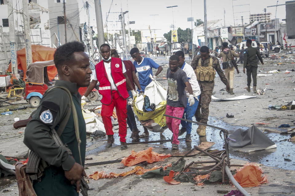 Rescuers remove a body from the scene of a double car-bomb attack in Mogadishu, Somalia, Saturday Oct. 29, 2022. Two car bombs exploded Saturday at a busy junction in Somalia's capital near key government offices, leaving "scores of civilian casualties," police told state media. (AP Photo/Farah Abdi Warsameh)