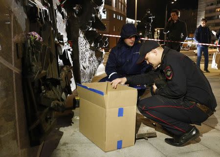 An Interior Ministry officer talks to a worker near a monument to Russian designer of the AK-47 assault rifle Mikhail Kalashnikov, after a fragment of the memorial was removed in Moscow, Russia September 22, 2017. REUTERS/Sergei Karpukhin