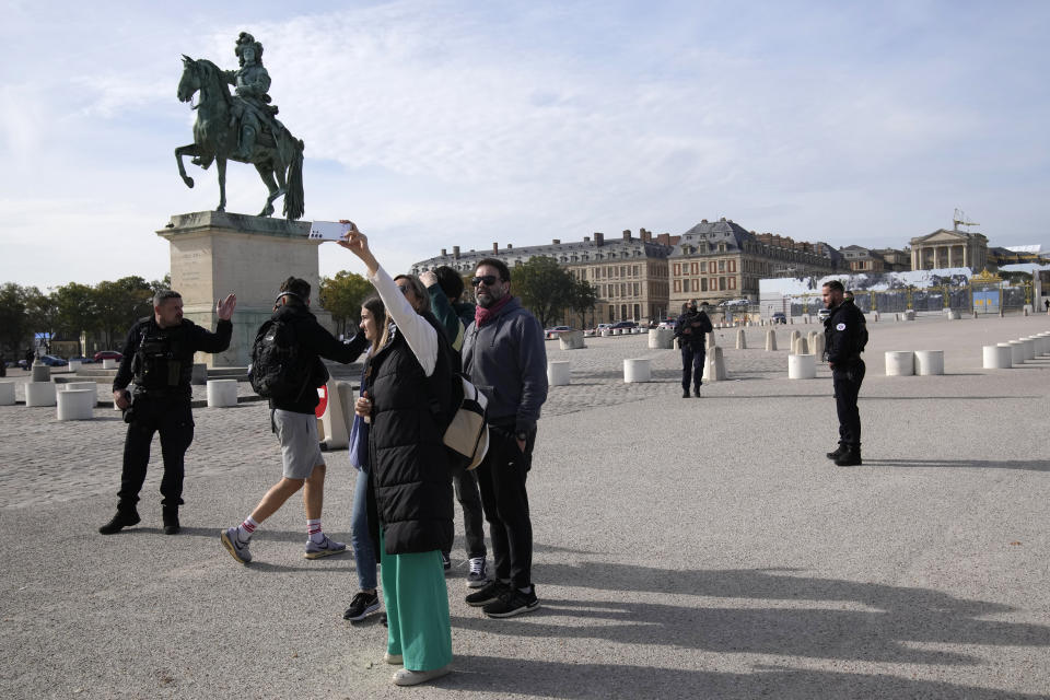 Tourists wait as French police officers guard the Chateau de Versailles after a security alert Tuesday, Oct. 17, 2023 in Versailles, west of Paris. The Palace of Versailles, one of France's most visited tourist attractions, is being evacuated for a security scare. It's the second time in four days the palace has had to close, with France on heightened alert against feared attacks after the fatal stabbing of a school teacher. (AP Photo/Christophe Ena)