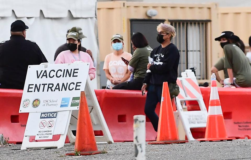 People wearing facemasks outdoors are seen at a Covid-19 vaccine site in Los Angeles, California on July 6, 2021. - A rapid rise in the 