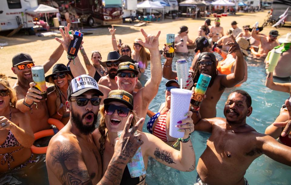 Gary Adams (left, front) and Baylie Pierson pose for a photo with new friends in a pool together in The Resort camping area at Stagecoach at the Empire Polo Club in Indio, Calif., Saturday, April 29, 2023. Adams and Pierson were attending Stagecoach for the first time with Pierson's parents who have been a handful of times. They made quick friends with their neighbors and joined in what was perhaps the largest pool on the grounds for the weekend. 