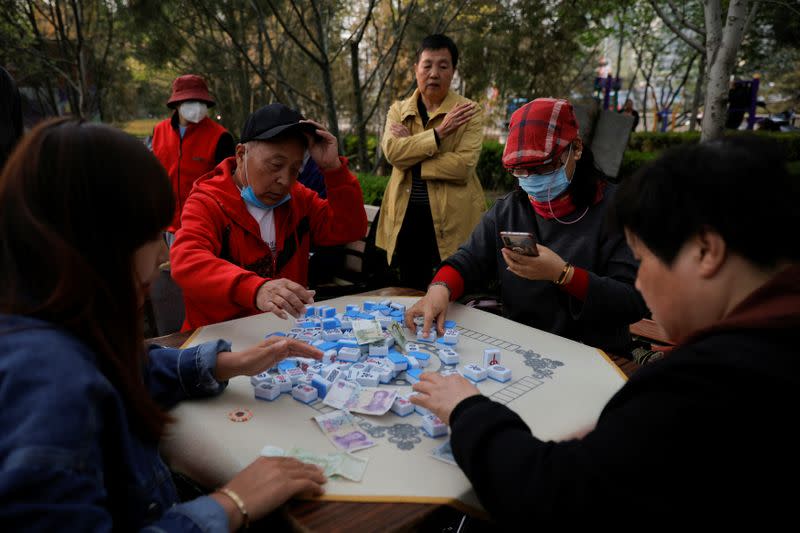 Elderly people play mahjong in a park in Beijing