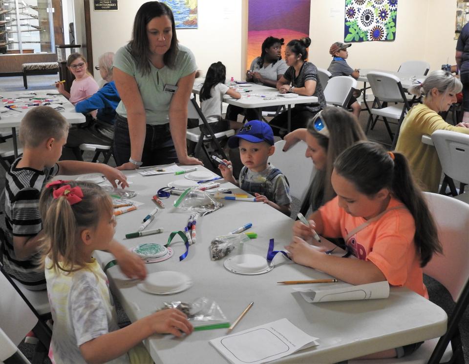 Jennifer Bush, executive director of the Johnson-Humrickhouse Museum, checks in with youth making a turtle rattle with paper plates, string and markers as part of a youth activity during a past summer program. The museum and other local organizations are offering a series of summer programming again this year.