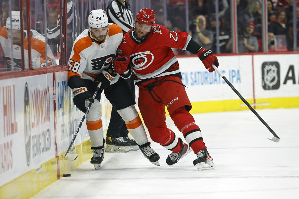 Carolina Hurricanes' Stefan Noesen (23) knocks Philadelphia Flyers' Tanner Laczynski (58) off the puck during the first period of an NHL hockey game in Raleigh, N.C., Thursday, March 9, 2023. (AP Photo/Karl B DeBlaker)