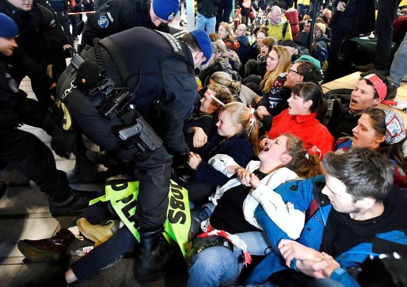 Demonstrators react in front of military police as Greenpeace stages a climate protest at Amsterdam Schiphol Airport in Schiphol