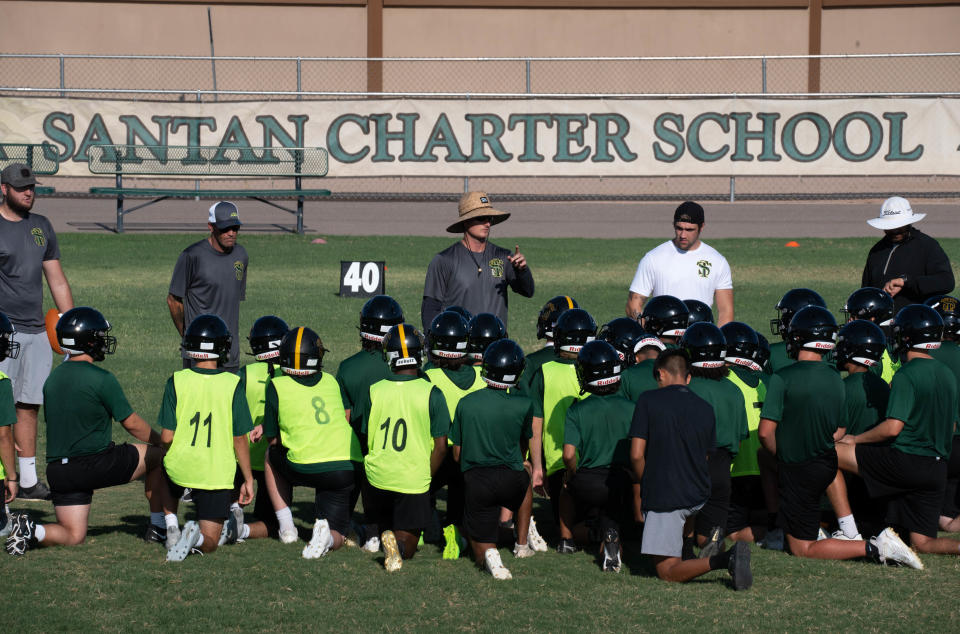 Chase Cartwright (head coach, center) talks with his players after practice on July 25, 2022, at San Tan Charter High School in Gilbert, Arizona.