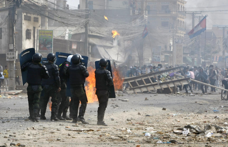 Cambodian riot police prepare to confront with garment workers throwing stones and bricks near a factory on the Stung Meanchey complex on the outskirts of Phnom Penh, Cambodia, Friday, Jan. 3, 2014. A police official says at least three people are dead and several wounded after police opened fire Friday to break up a labor protest by striking garment workers. (AP Photo/Heng Sinith)