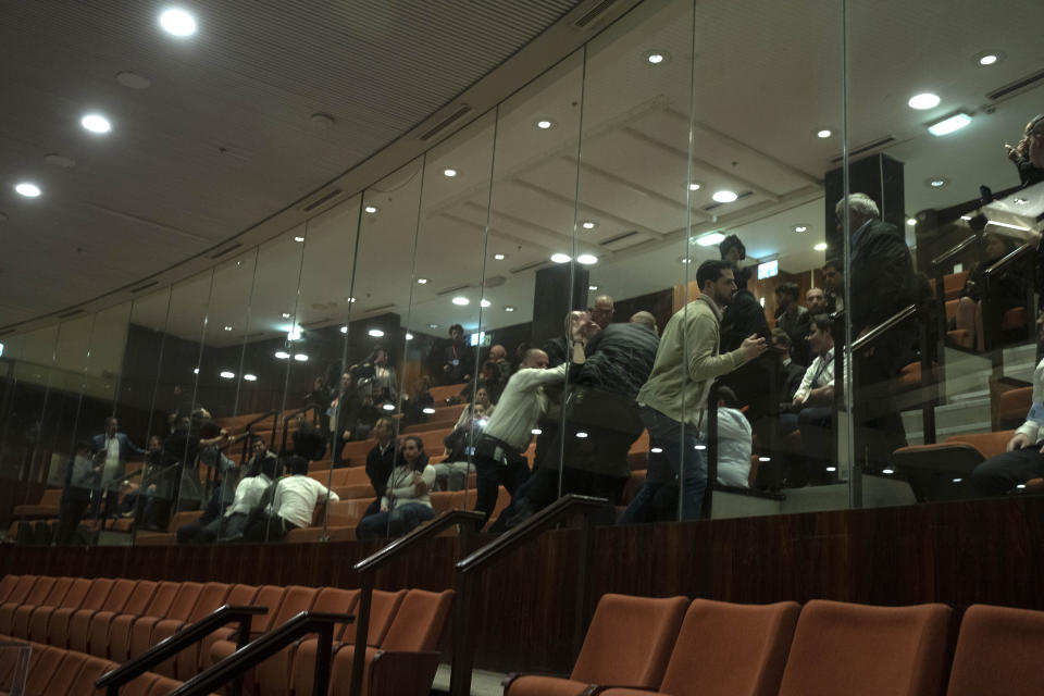 Protesters are subdued by security guards in the visitors gallery at Israel's parliament, the Knesset, as lawmakers vote on a contentious plan to overhaul the country's legal system, in Jerusalem, Monday, Feb. 20, 2023. (AP Photo/Maya Alleruzzo, Pool)