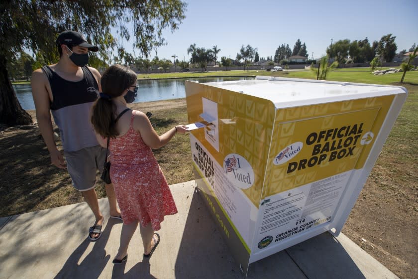 SANTA ANA, CA - OCTOBER 13: Caitlin Harjes, center, of Orange, and Angel Santiago, of Santa Ana, place their ballots inside an official Orange County Registrar of Voters ballot Drop Box for the 2020 Presidential General Election at Carl Thornton Park in Santa Ana on Tuesday, Oct. 13, 2020. (Allen J. Schaben / Los Angeles Times)