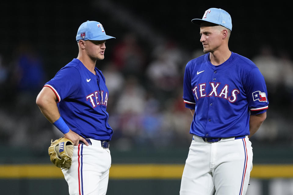 Texas Rangers third baseman Josh Jung, left, and shortstop Corey Seager, right, talk during a pitching change in the fourth inning of a spring training baseball game against the Boston Red Sox, Monday, March 25, 2024, in Arlington, Texas. (AP Photo/Sam Hodde)
