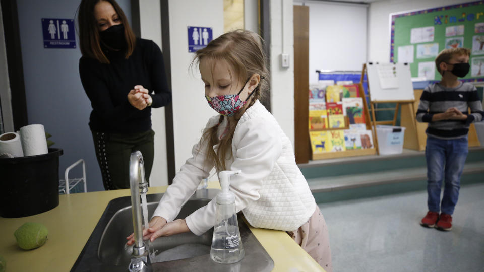 Kindergarten teacher assistant Susan Silic assist student with proper hand washing in the classroom at Lupine Hill Elementary School in Calabasas as one of the first elementary schools to open up under in L.A. County Monday morning. (Al Seib/Los Angeles Times via Getty Images)