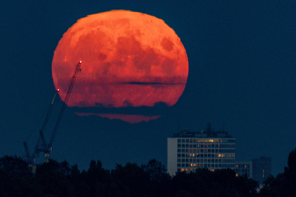A bright red full moon, known as the harvest moon, rising above Birmingham