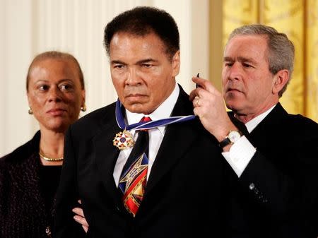 U.S. President George W. Bush (R) awards boxing legend Muhammad Ali (C) with the Presidential Medal of Freedom, as Ali's wife Lonnie watches, during a ceremony in the East Room of the White House in Washington in this November 9, 2005 file photo. REUTERS/Kevin Lamarque/Files