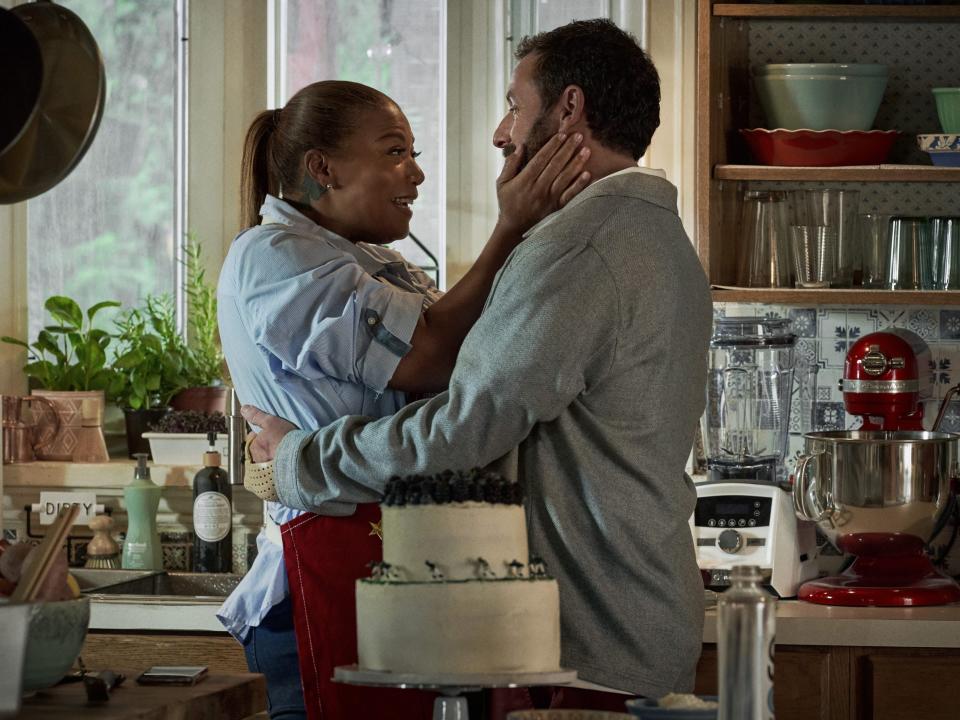 Queen Latifah holding Adam Sandler's face while they are in a kitchen