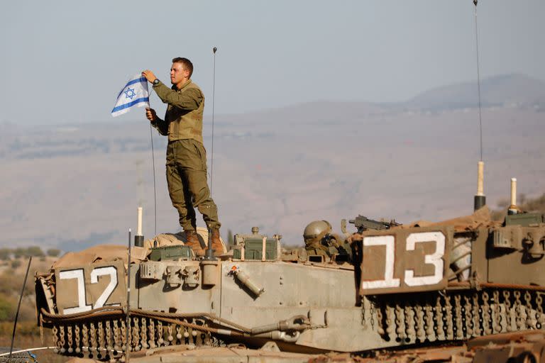 Un soldado israelí coloca una bandera nacional sobre un tanque Merkava durante un ejercicio militar cerca de la frontera con Líbano, en la región de la Alta Galilea, en el norte de Israel.