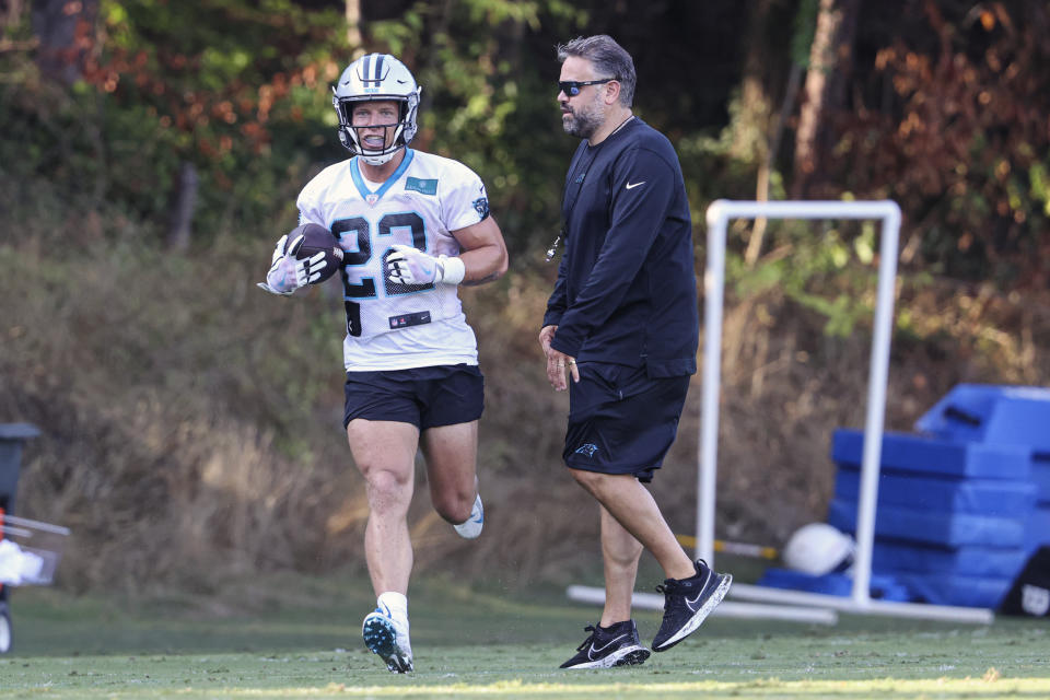 Carolina Panthers running back Christian McCaffrey, left, runs past head coach Matt Rhule at the NFL football team's training camp in Spartanburg, S.C., Wednesday, July 28, 2021. (AP Photo/Nell Redmond)